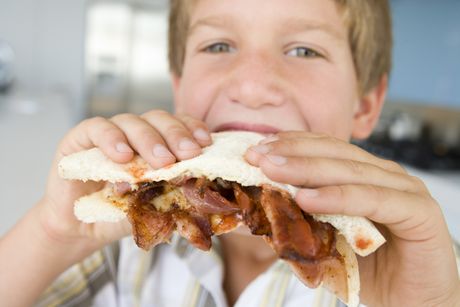 Boy eating bacon sandwich at home dečak sendvič sa slaninom slanina