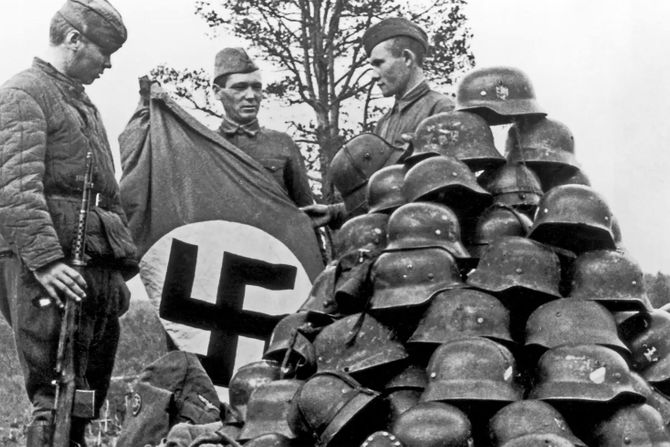 Ruski vojnici sa zaplenjenim nacisctičkim šlemovima i zastavama